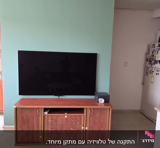 טלוויזיה מותקנת על קיר עם ארונית עץ מתחת